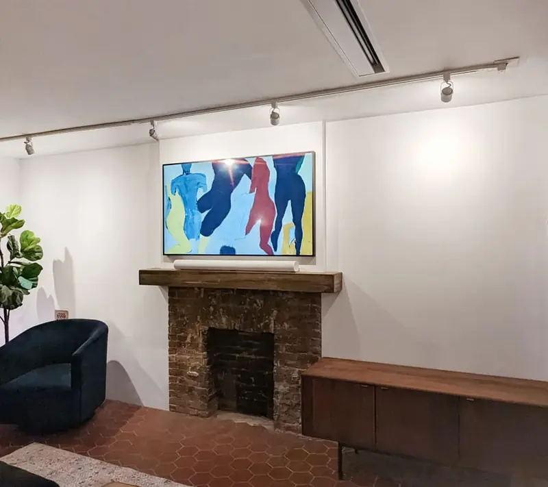 Frame TV mounted over a brick fireplace with a reclaimed wood mantel