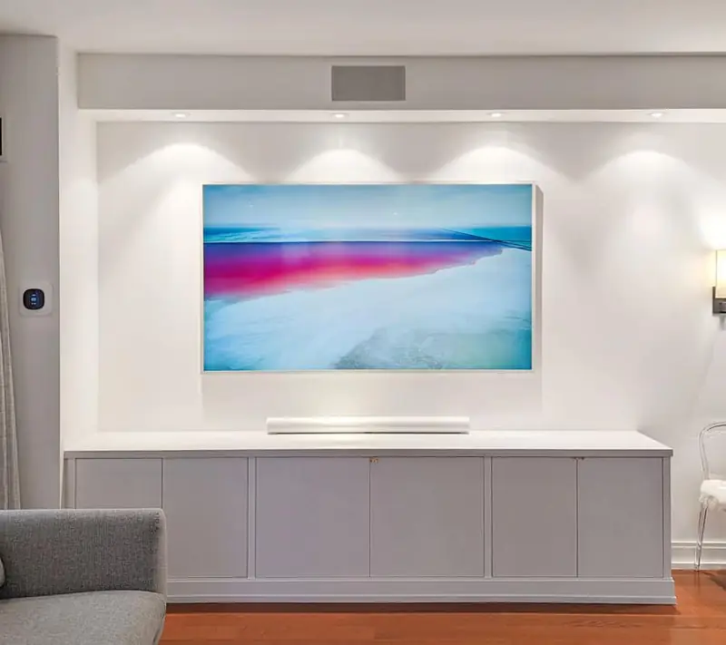 Frame TV with a white bezel over a walnut credenza, mounted flush to the wall